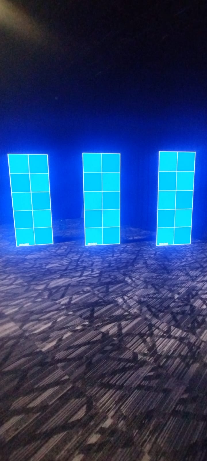 Três totens LED verticais separados, exibindo grades de teste.