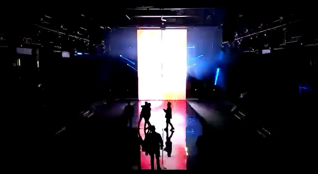 Scène avec écran LED vertical et reflets au sol pendant une présentation